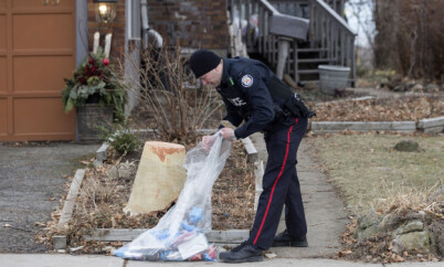 FILE - In this Jan. 29 , 2018 file photo, a police officer investigates outside a home on Mallory Crescent in Toronto, Canada, where Bruce McArthur did landscape work. Police said Thursday, Feb. 8, that they have recovered the remains of at least six people from planters on the property. A Toronto detective said the remains, found on property McArthur used as storage in exchange for doing the landscaping, included some from one of the five men McArthur is already charged with killing, Andrew Kinsman. (Chris Young/The Canadian Press via AP File)